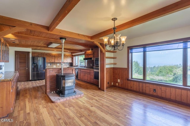 kitchen featuring wall oven, brown cabinets, beamed ceiling, wainscoting, and refrigerator with ice dispenser