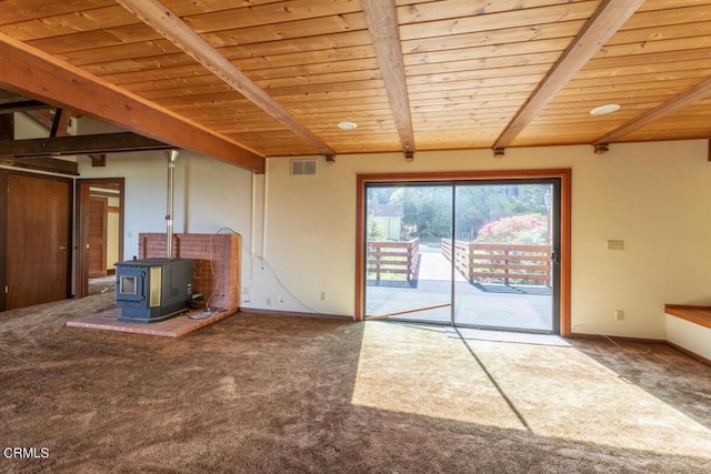 unfurnished living room featuring a wood stove, carpet, visible vents, and beamed ceiling