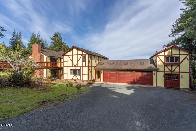tudor home with a garage, aphalt driveway, and stucco siding