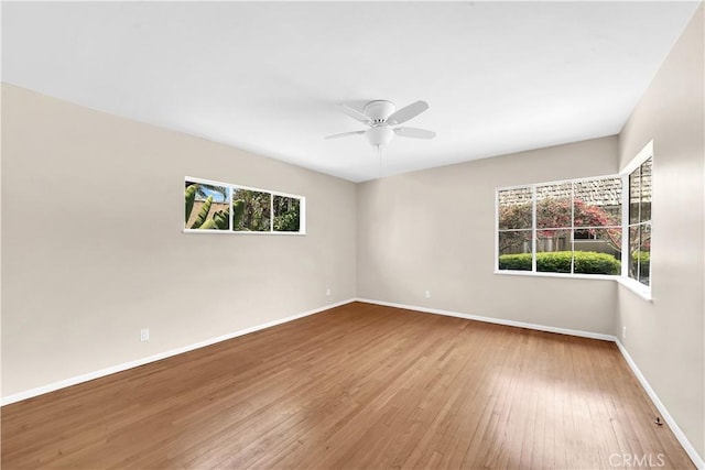 spare room with ceiling fan, a healthy amount of sunlight, and wood-type flooring