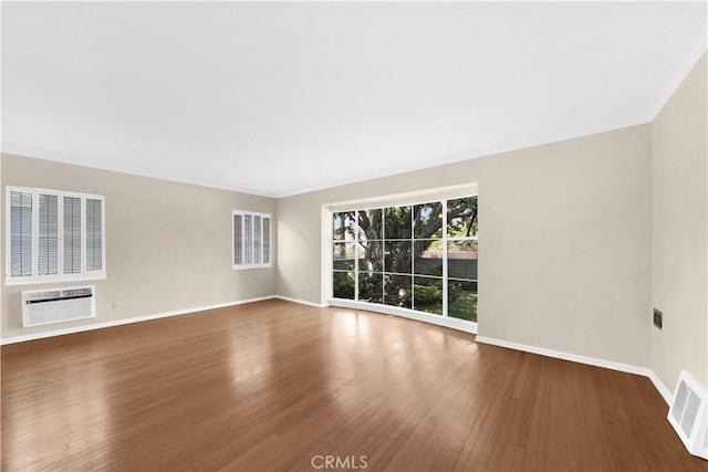 spare room featuring a wall mounted air conditioner and wood-type flooring