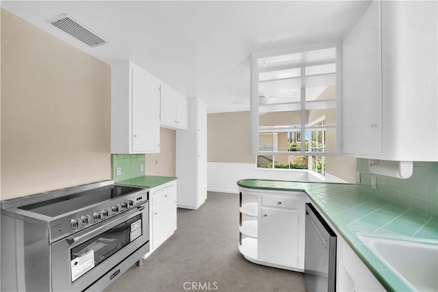 kitchen featuring tile countertops, tasteful backsplash, sink, white cabinets, and stainless steel appliances