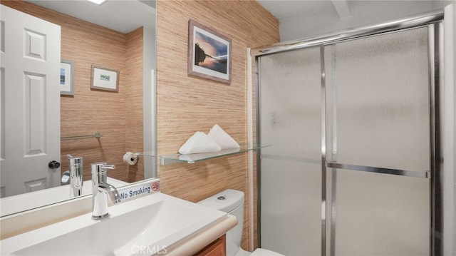 bathroom with wooden walls, vanity, a shower with shower door, and toilet