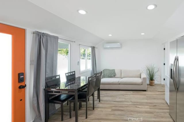 dining space featuring light hardwood / wood-style floors, an AC wall unit, and lofted ceiling