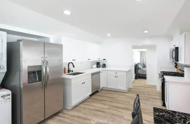 kitchen featuring appliances with stainless steel finishes, white cabinetry, sink, and light wood-type flooring