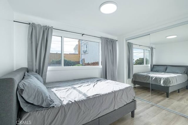 bedroom with a closet, multiple windows, and light hardwood / wood-style floors