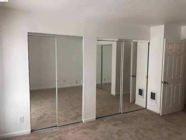 unfurnished bedroom featuring carpet floors and two closets