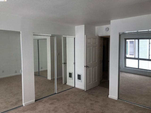 unfurnished bedroom featuring multiple closets and carpet