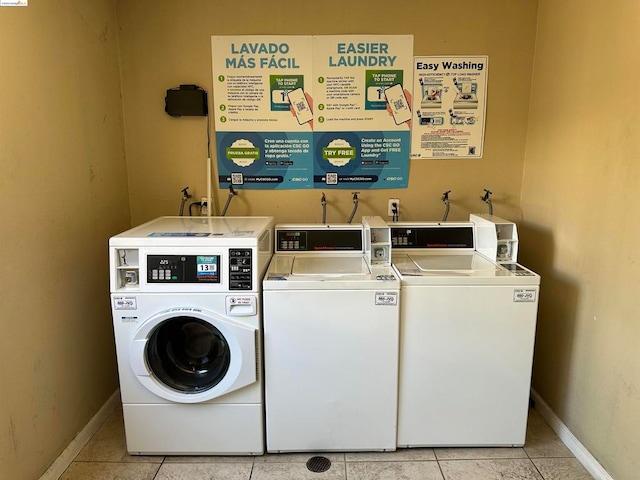 clothes washing area featuring light tile patterned flooring and washing machine and clothes dryer