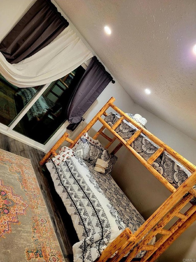 bedroom with vaulted ceiling, dark hardwood / wood-style flooring, and a textured ceiling