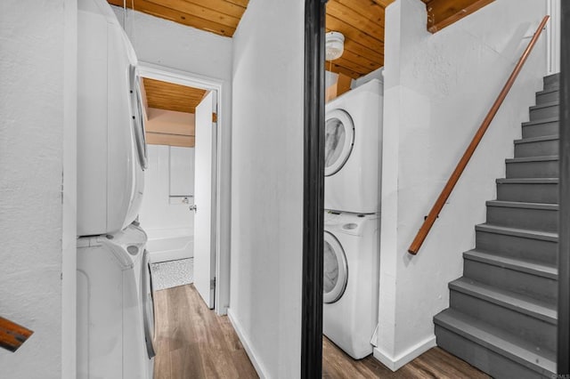 laundry room featuring hardwood / wood-style flooring, wooden ceiling, and stacked washer and dryer