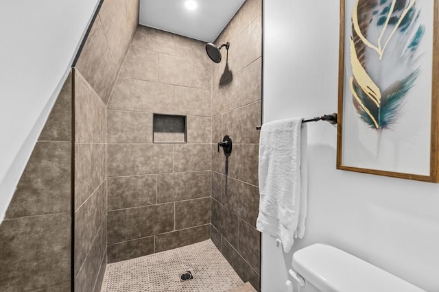 bathroom featuring a tile shower and toilet