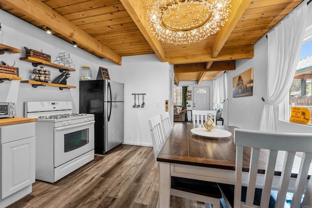 kitchen featuring stainless steel fridge, white gas range oven, wood-type flooring, beam ceiling, and white cabinets