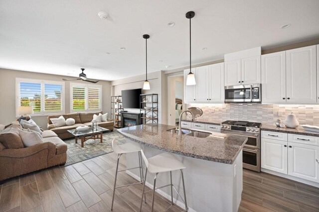 kitchen featuring white cabinetry, stainless steel appliances, sink, and dark stone counters