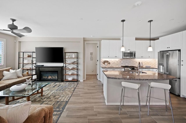 kitchen featuring stainless steel appliances, white cabinetry, sink, and decorative light fixtures