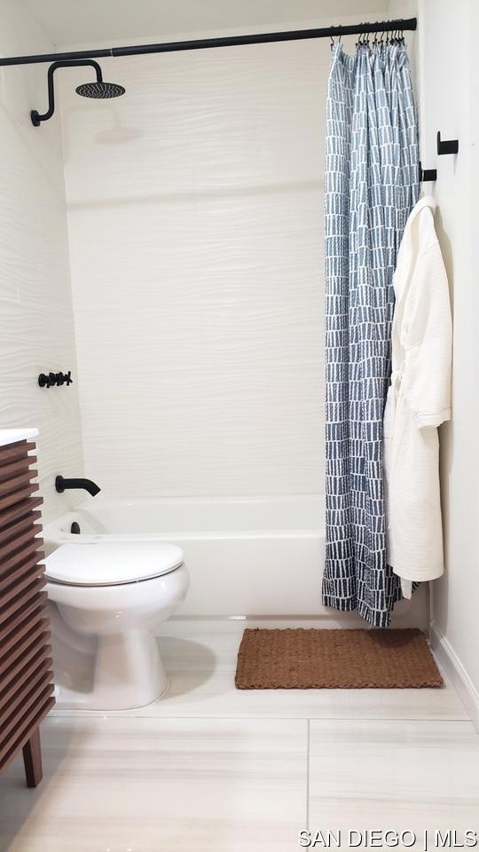 bathroom featuring tile patterned flooring, shower / bath combo with shower curtain, and toilet