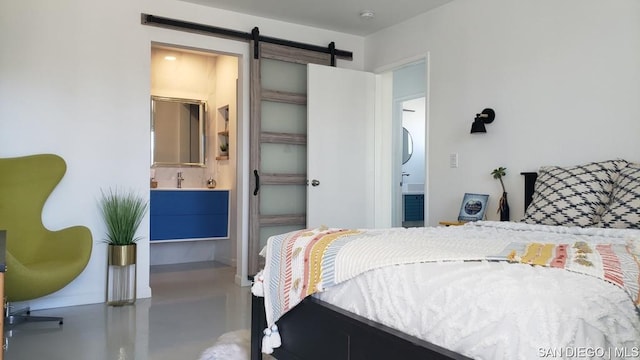 bedroom featuring ensuite bath, concrete flooring, and a barn door