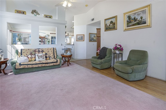 living room with ceiling fan, a towering ceiling, and carpet floors