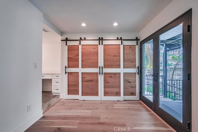 doorway to outside featuring a barn door, a healthy amount of sunlight, and light hardwood / wood-style flooring