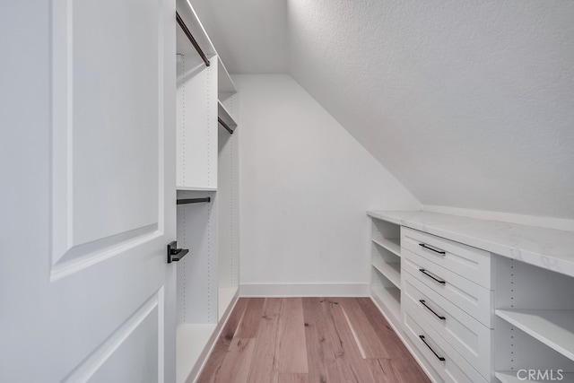 walk in closet featuring vaulted ceiling and light hardwood / wood-style flooring