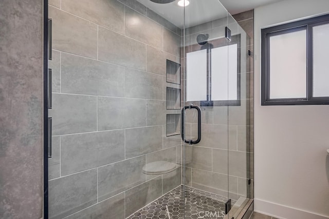 bathroom featuring a shower with shower door, ceiling fan, and toilet