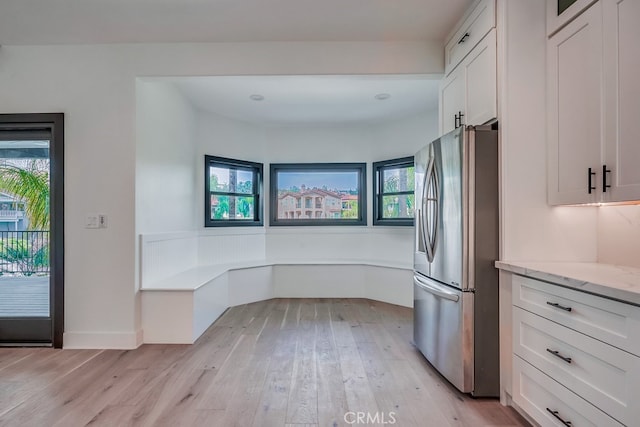 kitchen with plenty of natural light, light hardwood / wood-style floors, white cabinetry, and stainless steel refrigerator with ice dispenser