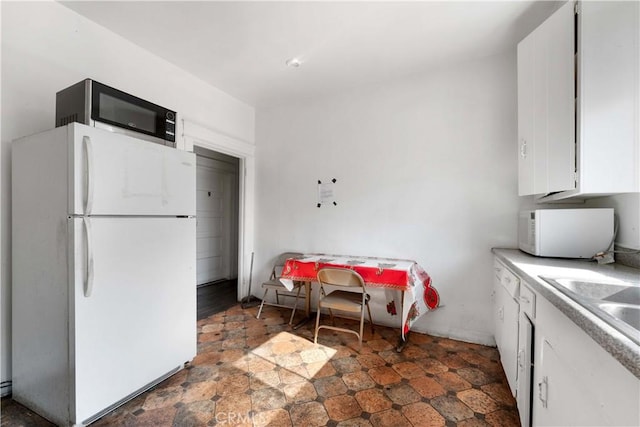 kitchen featuring white appliances, white cabinetry, and sink