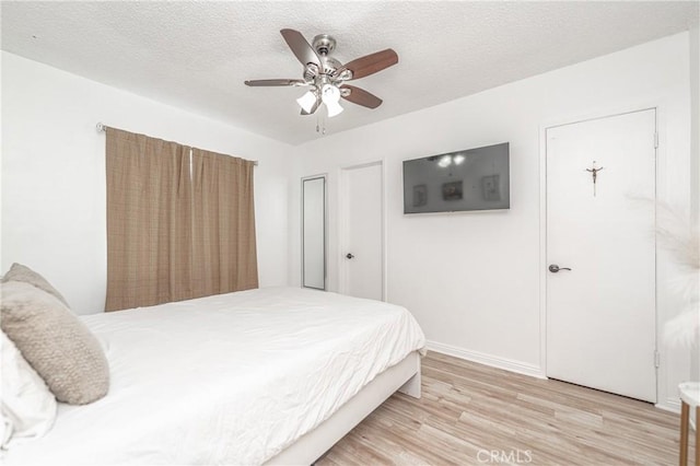 bedroom featuring ceiling fan, light wood-type flooring, and a textured ceiling