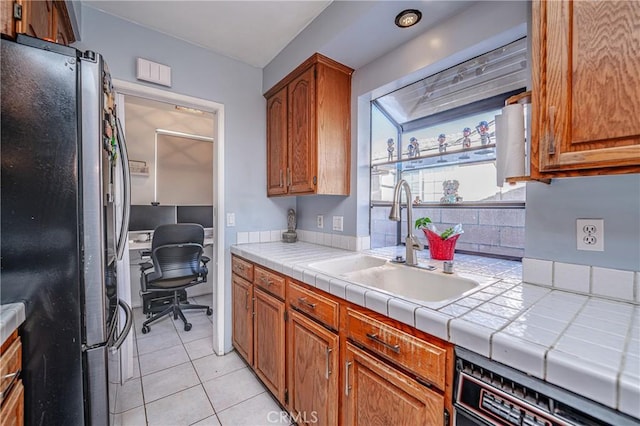 kitchen featuring sink, tile countertops, fridge, dishwashing machine, and light tile patterned flooring