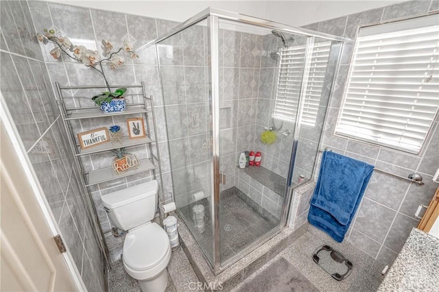 bathroom with tile walls, an enclosed shower, and toilet