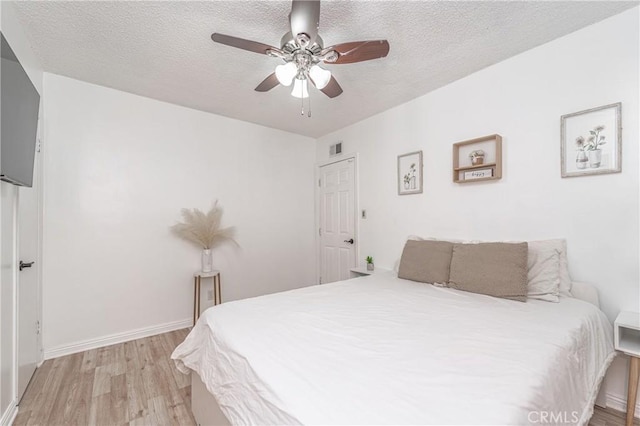 bedroom with ceiling fan, light wood-type flooring, and a textured ceiling