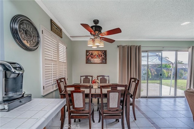 dining area with tile patterned flooring, ceiling fan, ornamental molding, and a textured ceiling