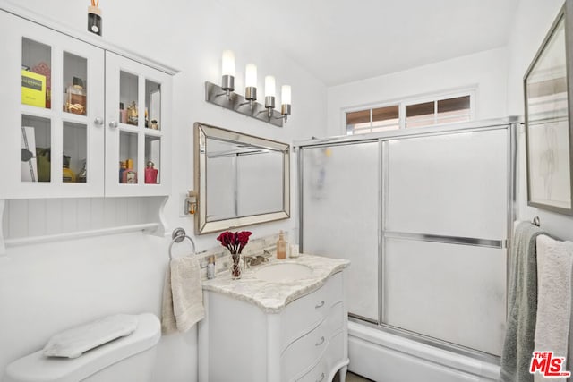 full bathroom featuring toilet, large vanity, and bath / shower combo with glass door