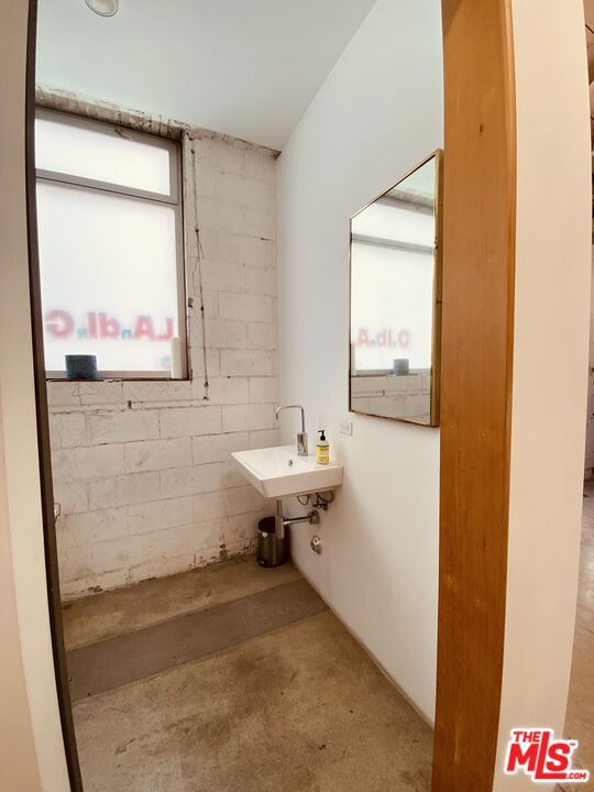 bathroom featuring a healthy amount of sunlight, sink, and concrete flooring