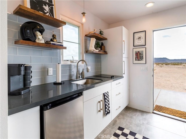 kitchen featuring decorative backsplash, sink, white cabinets, and stainless steel dishwasher