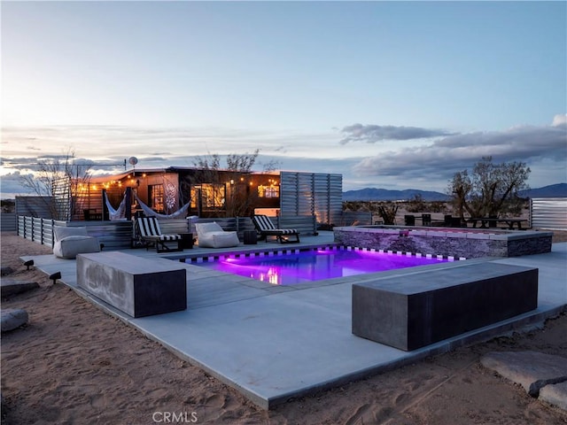 pool at dusk with a mountain view and a patio area