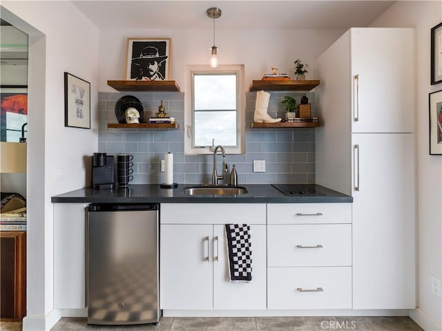 kitchen featuring stainless steel refrigerator, white cabinetry, sink, tasteful backsplash, and pendant lighting