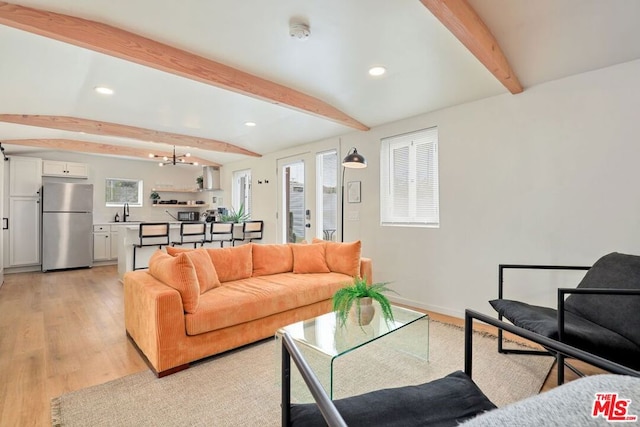 living room with sink, beamed ceiling, and light wood-type flooring