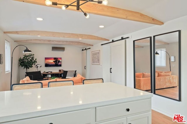 kitchen featuring a barn door, lofted ceiling with beams, white cabinetry, and light hardwood / wood-style floors