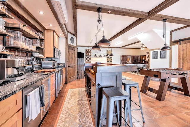 kitchen with tasteful backsplash, a barn door, beamed ceiling, decorative light fixtures, and dark stone countertops