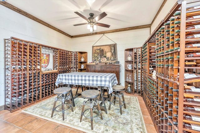 wine area featuring crown molding, light tile patterned flooring, and ceiling fan