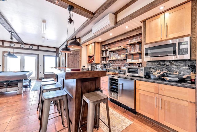 kitchen with hanging light fixtures, light brown cabinetry, a kitchen bar, a wall mounted air conditioner, and beamed ceiling