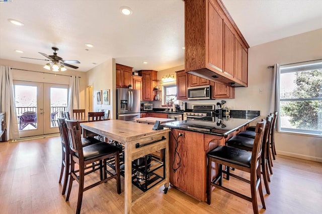 kitchen with french doors, light hardwood / wood-style flooring, kitchen peninsula, appliances with stainless steel finishes, and ceiling fan