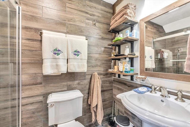 bathroom featuring toilet, wood walls, walk in shower, and sink