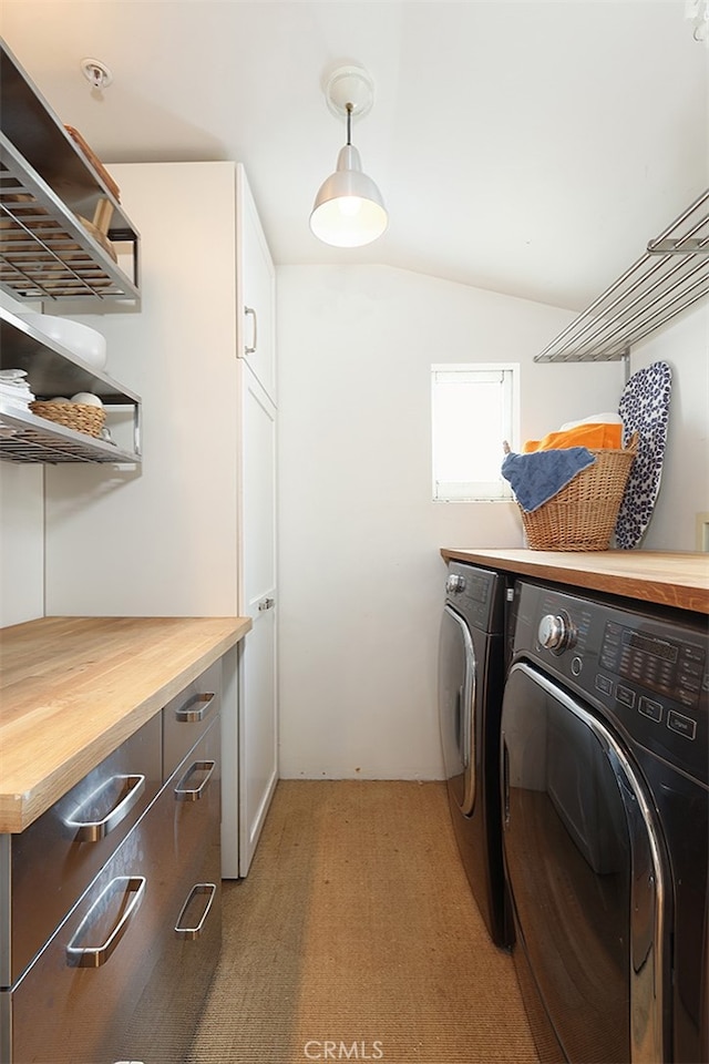 washroom featuring cabinets, washing machine and dryer, and light carpet