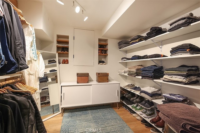 walk in closet with light hardwood / wood-style floors