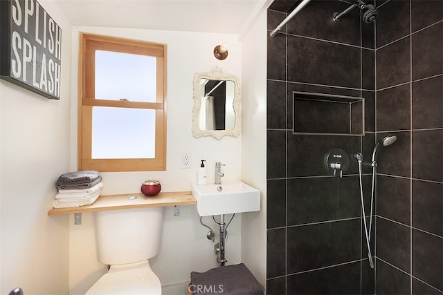 bathroom featuring sink, toilet, and tiled shower