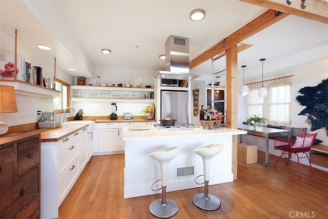 kitchen featuring island exhaust hood, stainless steel appliances, light hardwood / wood-style flooring, white cabinetry, and hanging light fixtures