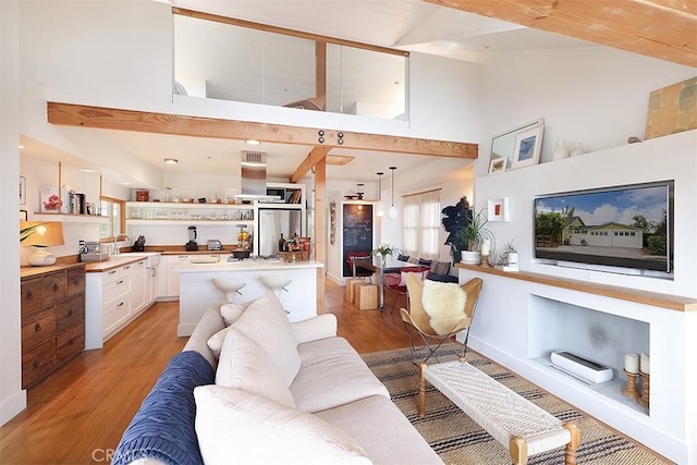 living room with beam ceiling, high vaulted ceiling, and light hardwood / wood-style floors