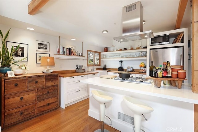 667 Glenneyre St, Laguna Beach, CA 92651 - kitchen with white cabinetry, a kitchen bar, open shelves, island exhaust hood, and white gas stovetop